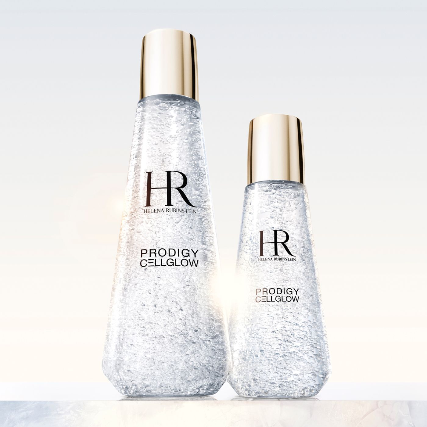 Helena Rubinstein Prodigy Cellglow: la esencia de una piel regenerada. Dos frascos de pureza cristalina, sus finas burbujas reflejando la luz, prometen un renacimiento de luminosidad y vitalidad. El arte de la luz en la piel.