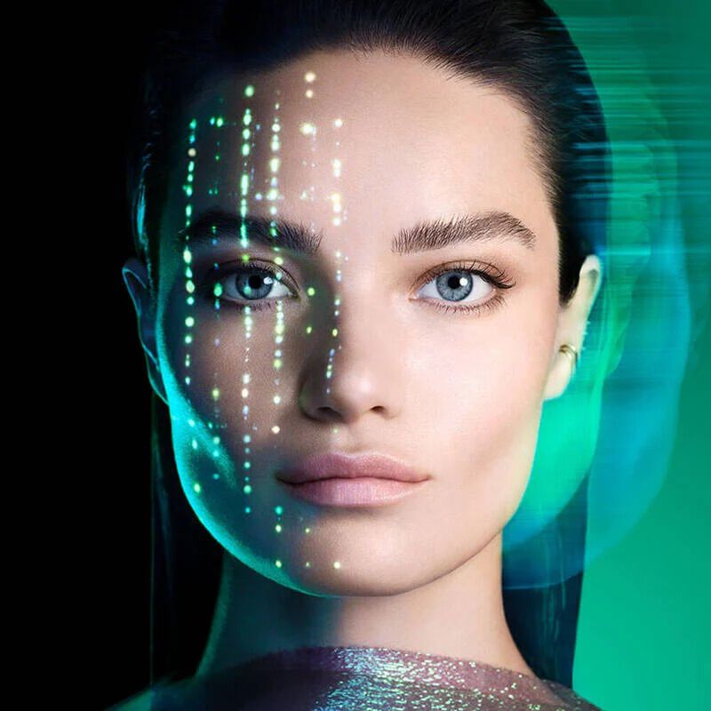 una mujer de cabello oscuro y ojos azules, con la mirada fija al frente, sobre un fondo verde