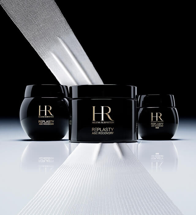 Tres tarros negros de crema Helena Rubinstein Re-Plasty Age Recovery, uno grande en el centro y dos mas pequenos a los lados, con bandas blancas que evocan vendajes, sobre un fondo oscuro.