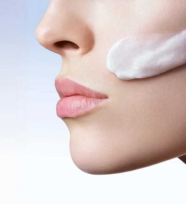 Perfil de una mujer desde la nariz hasta el menton con la textura de una crema en la mejilla.