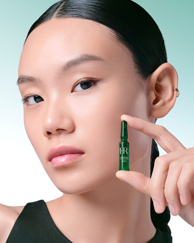 Modelo que sostiene una ampolla verde de Powercell Skinmunity EXO.