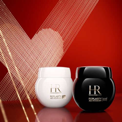 Foto del producto de la Crema de Dia Re-Plasty Age Recovery y la Crema de Noche Re-Plasty Age Recovery de Helena Rubinstein, en un tarro blanco brillante y un tarro negro brillante respectivamente. Los tarros estan colocados uno al lado del otro sobre una superficie roja reflectante, con un fondo rojo intenso decorado con un corazon de arte lineal dorado.​
