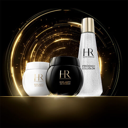  Cremas Helena Rubinstein Re-Plasty Age Recovery (tarros blancos y negros) y una botella Prodigy Cellglow, sobre un fondo de luz dorada brillante sobre negro.