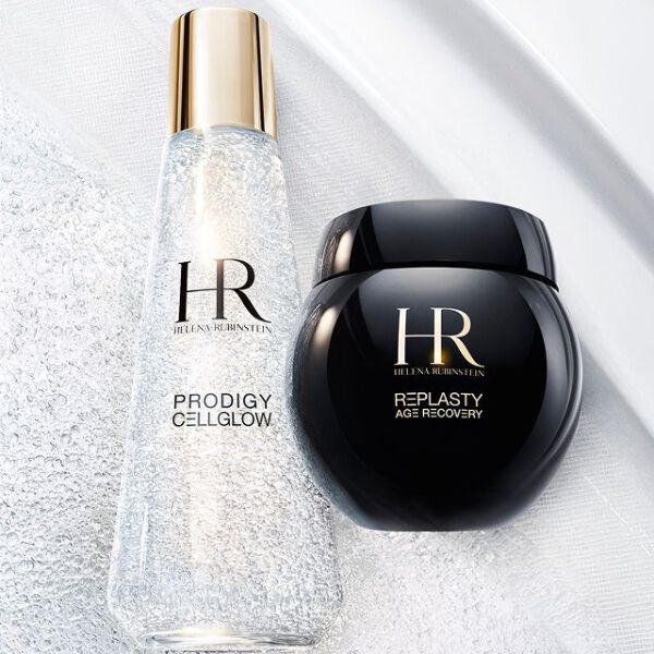 Frasco de serum Prodigy Cellglow (claro, burbujas) y tarro de crema Re-Plasty (negro) de Helena Rubinstein. Colocados sobre un fondo blanco texturizado y luminoso, simbolizando elegancia y eficacia del cuidado.