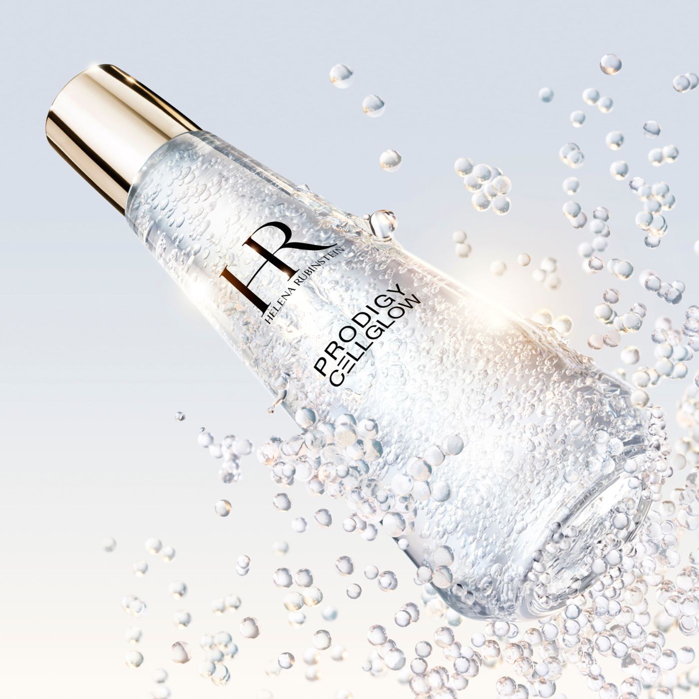  Frasco de suero "Helena Rubinstein Prodigy Cellglow" lleno de burbujas, inclinado y rodeado de burbujas brillantes suspendidas, sobre un fondo claro y luminoso.