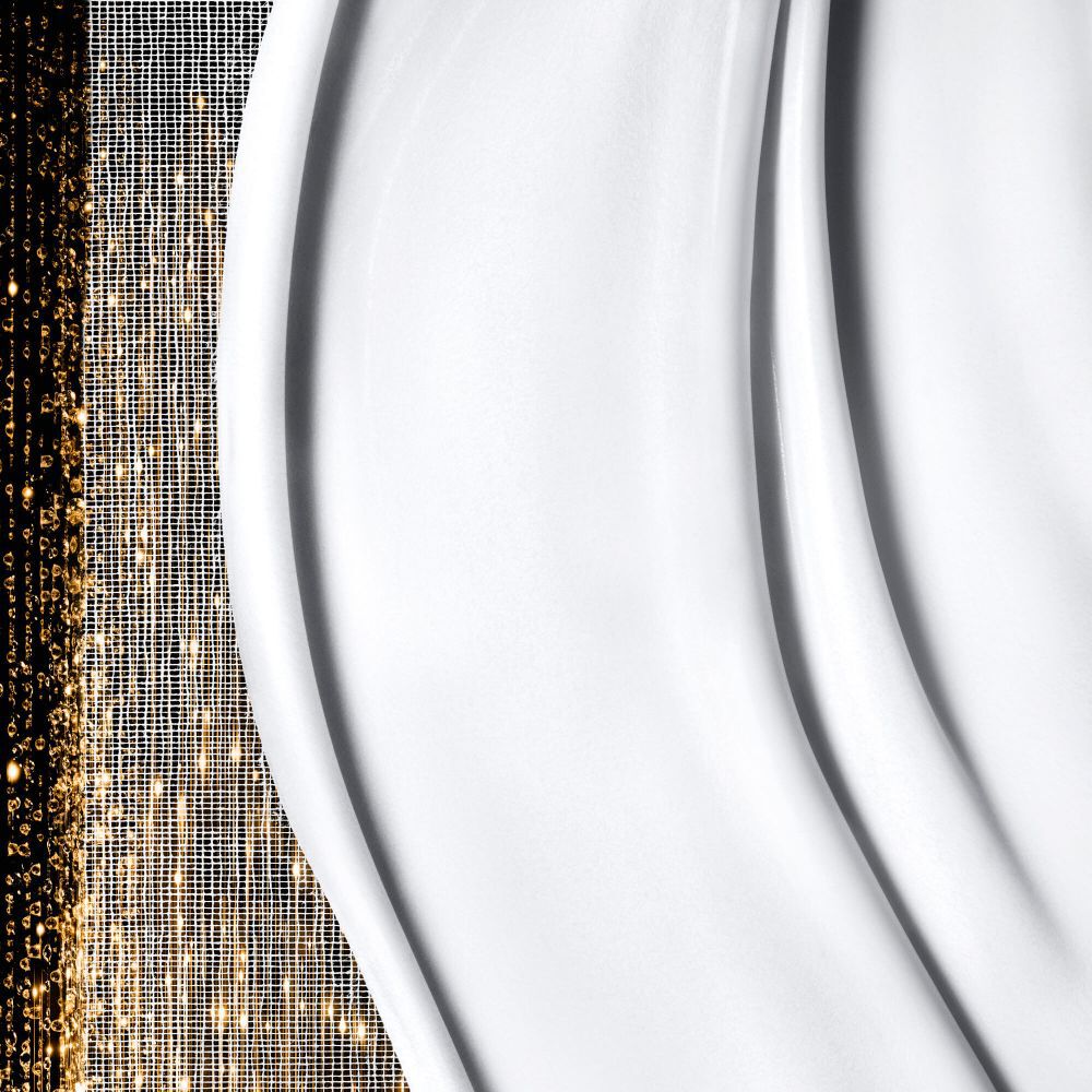 Textura blanca suave y cremosa con ondas suaves a la derecha, yuxtapuesta con patrones dorados brillantes y abstractos a la izquierda.