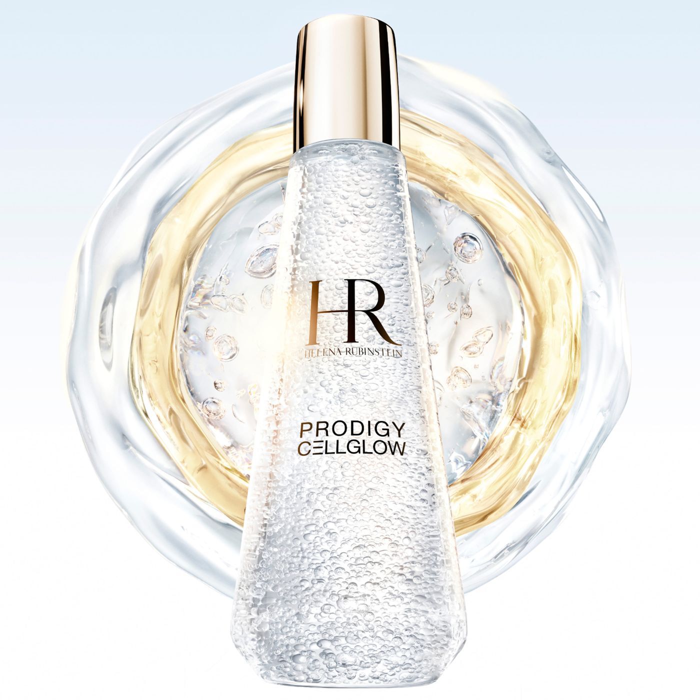 Frasco de suero "Helena Rubinstein Prodigy Cellglow" lleno de burbujas, centrado dentro de anillos liquidos translucidos y dorados que se extienden sobre un fondo claro.